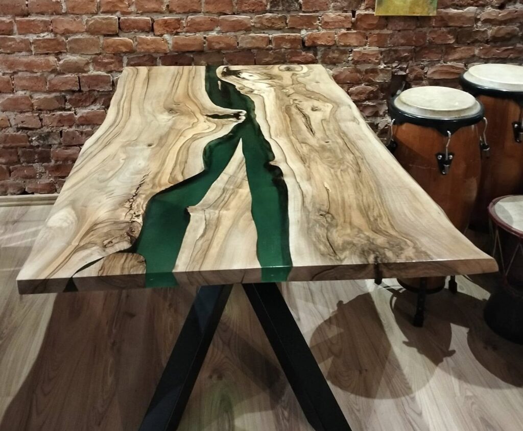 Duży stolik kawowy typu river table z litego drewna z głębokimi pęknięciami zalany niebieską żywicą epoksydową. Rękodzieło Warsztat z Drewna, wykadrowany na stół